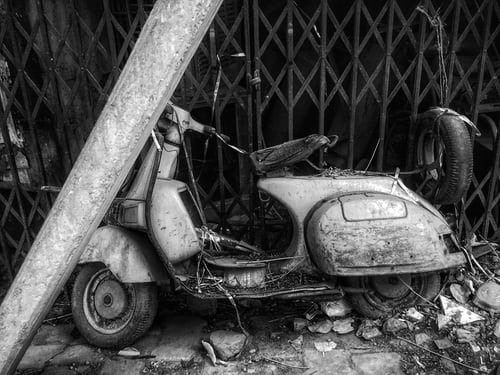 Black and white image of broken motorcycle.