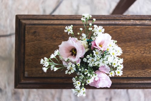 Dark brown wooden casket with pink flowers laid on top.