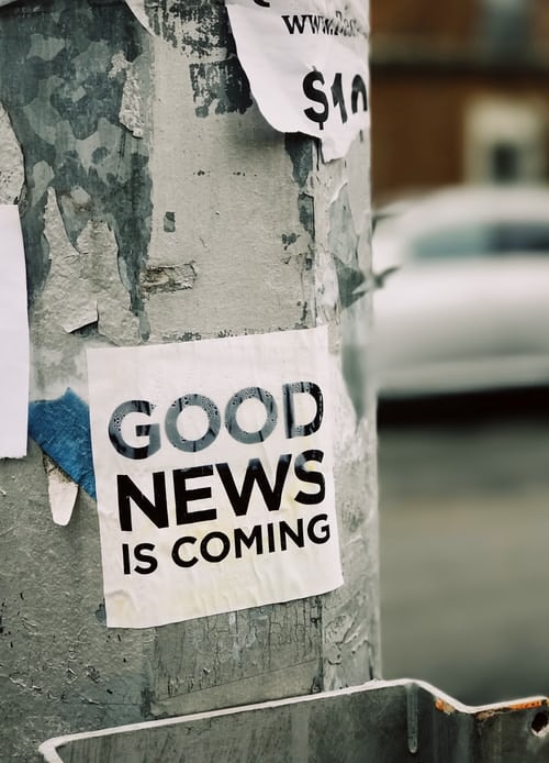 An old street post with a flyer saying good news is coming